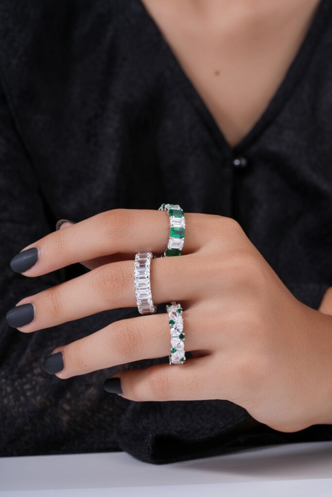 Close-up of elegant rings with diamonds and emeralds on a hand, perfect for fashion and jewelry photography.