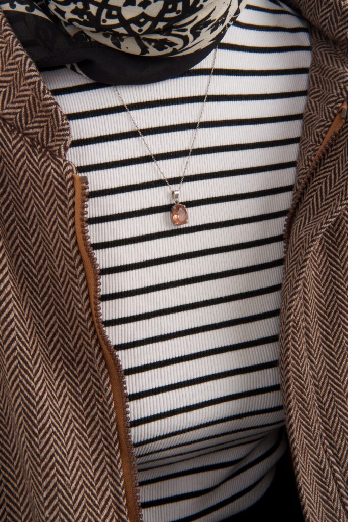 Detailed look at a striped top, necklace, and patterned jacket.